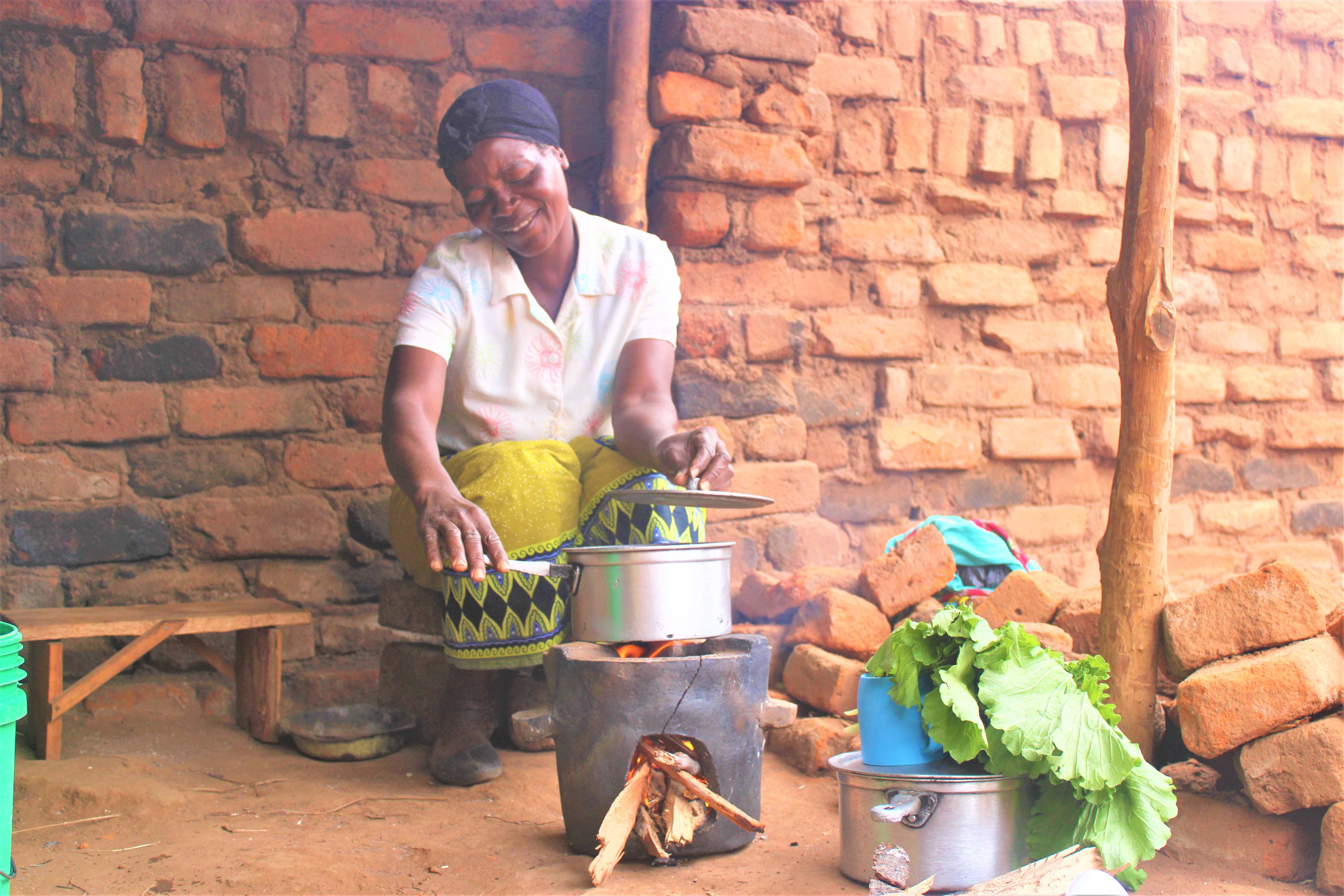 A community member smiles as she demonstrates the cookstove. Credit: Felix Malamula (PRIDE)